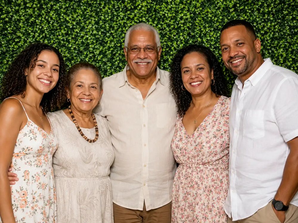 Multi-generational family smiling at a garden hedge backdrop photo booth at an outdoor celebration in Hampton