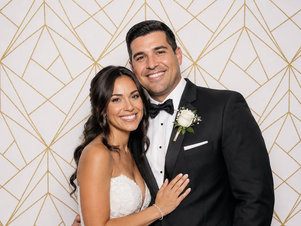 Bride and groom posing at a gold geometric backdrop photo booth at a wedding in Chesapeake