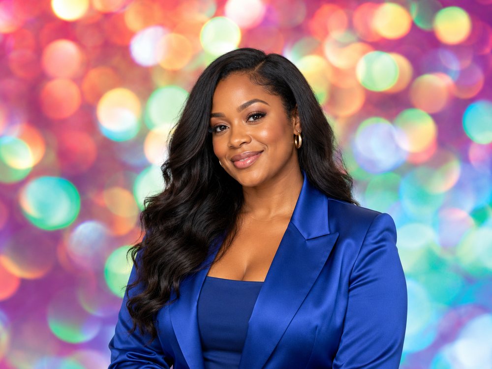 A guest in a cobalt satin blazer smiling at a multicolor neon bokeh backdrop photo booth at a birthday party in Newport News