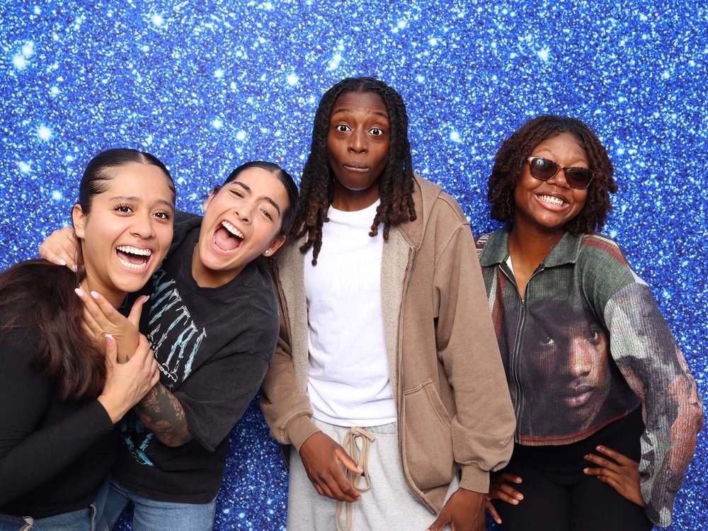 Four friends laughing at a Pixie Dust blue glitter backdrop at a Navy team event at Topgolf in Virginia Beach
