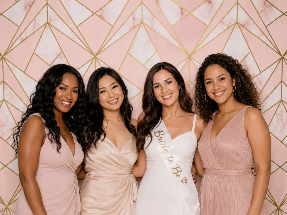 Bridal party in blush gowns posing at a rose gold marble backdrop photo booth at a bridal shower in Richmond