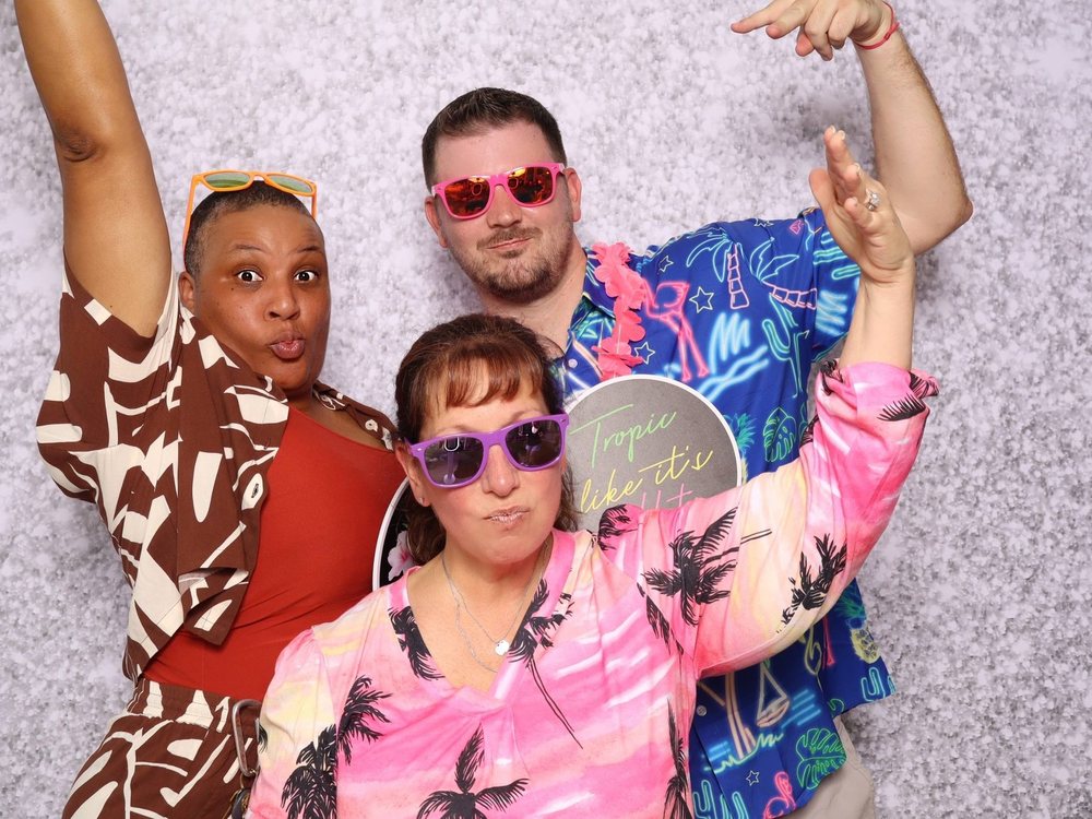 Friends in tropical shirts and heart sunglasses at a silver sparkle backdrop pool party photo booth in Newport News