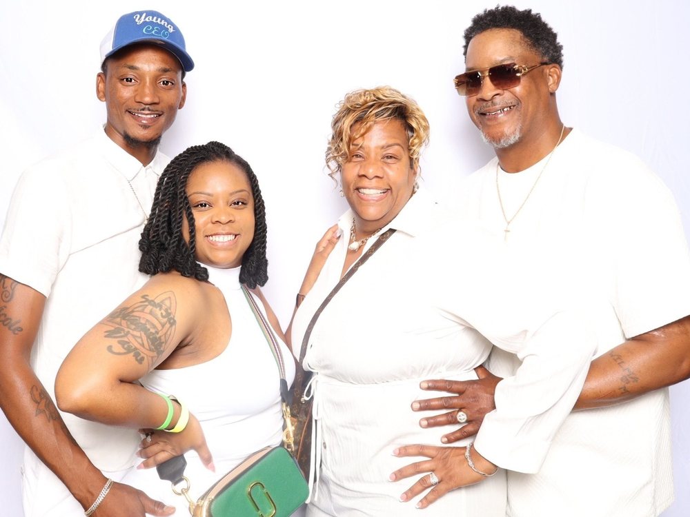 Four friends dressed in white posing at an all-white beach party photo booth in Virginia Beach