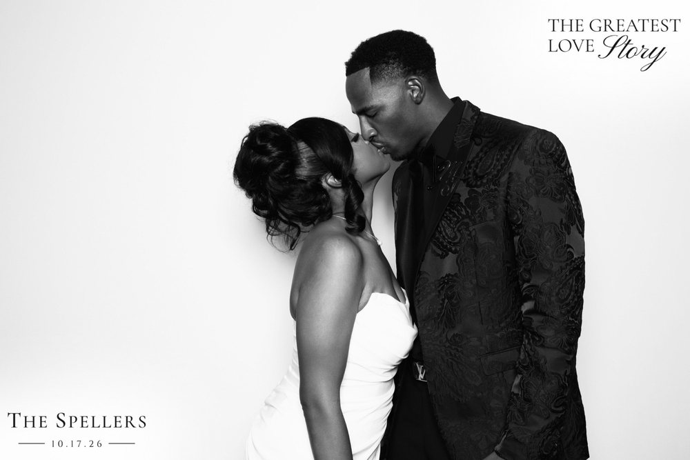 Trequan kissing Makima on the cheek at their black-and-white wedding photo booth at the Signet Center in Chesapeake