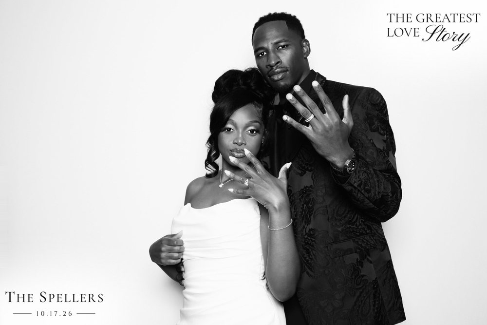 Makima and Trequan showing off their wedding rings at their black-and-white wedding photo booth at the Signet Center in Chesapeake
