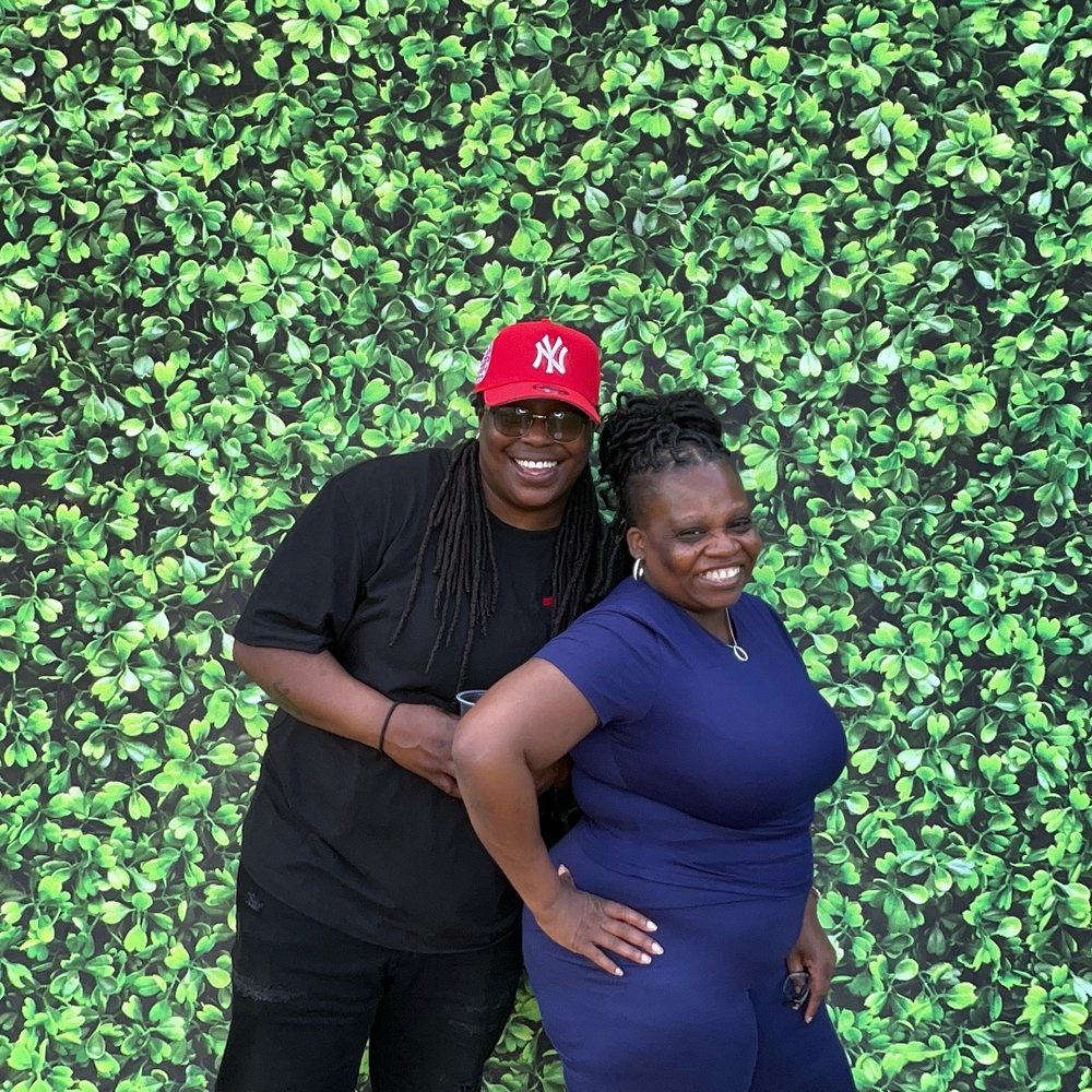 Two friends in a red Yankees cap and navy top smiling at an Easter family barbecue photo booth in Colerain, North Carolina