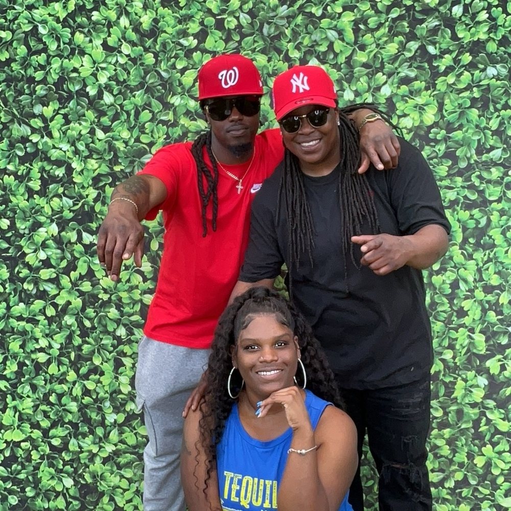 Three friends in red caps and sunglasses posing at an Easter family barbecue photo booth in Colerain, North Carolina