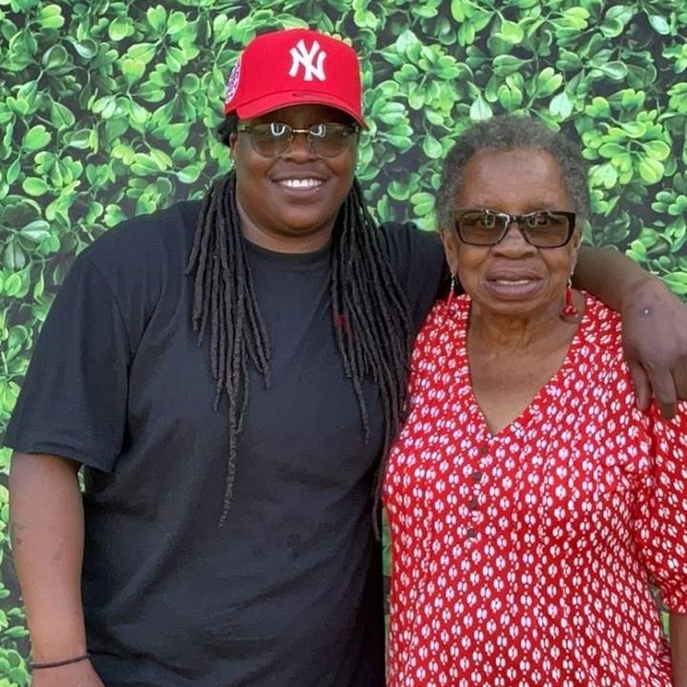 A grandmother and a guest in a red cap smiling together at an Easter family barbecue photo booth in Colerain, North Carolina