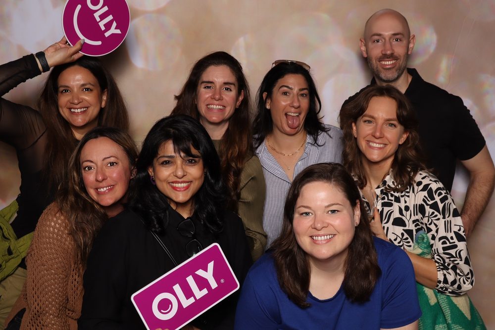 A team holding an OLLY sign at a corporate event photo booth in San Francisco