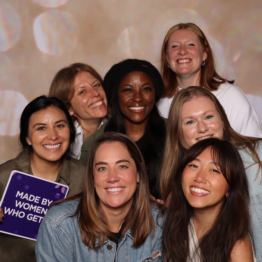 A group of women with a Made By Women sign at a corporate offsite photo booth in San Francisco
