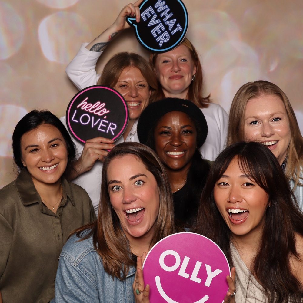 Coworkers with Hello Lover and OLLY signs at a corporate event photo booth in San Francisco