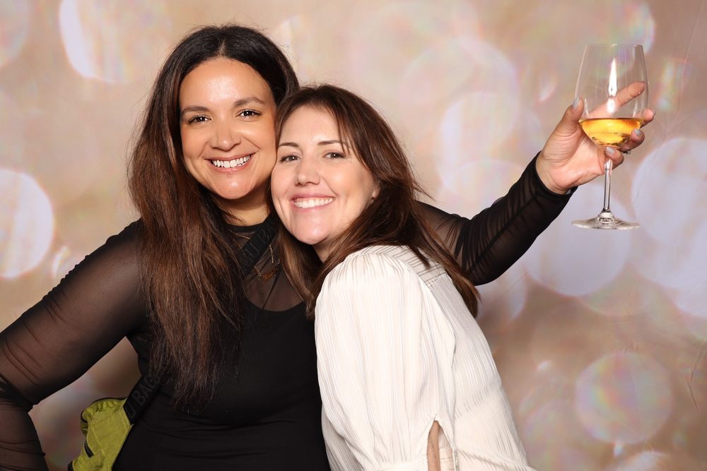 Two coworkers raising a glass at a corporate offsite photo booth in San Francisco