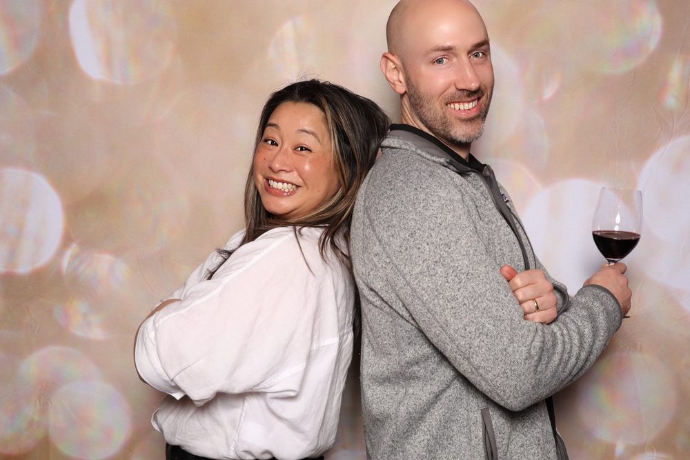Two coworkers posing back to back at a corporate event photo booth in San Francisco