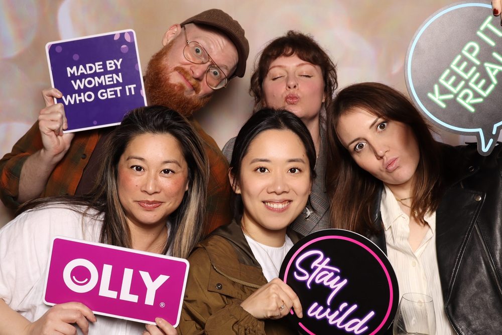 A team holding OLLY branded props at a corporate offsite photo booth in San Francisco