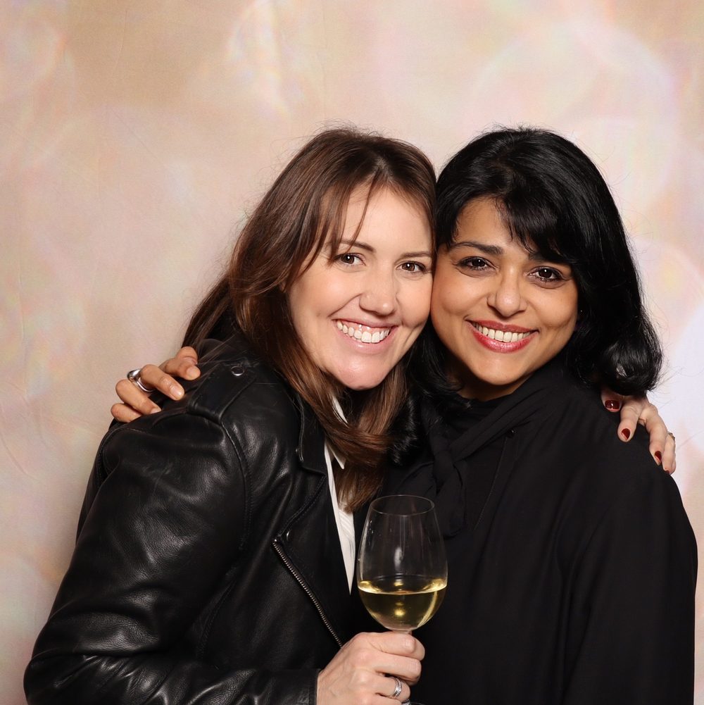 Two friends smiling at a corporate offsite photo booth in San Francisco