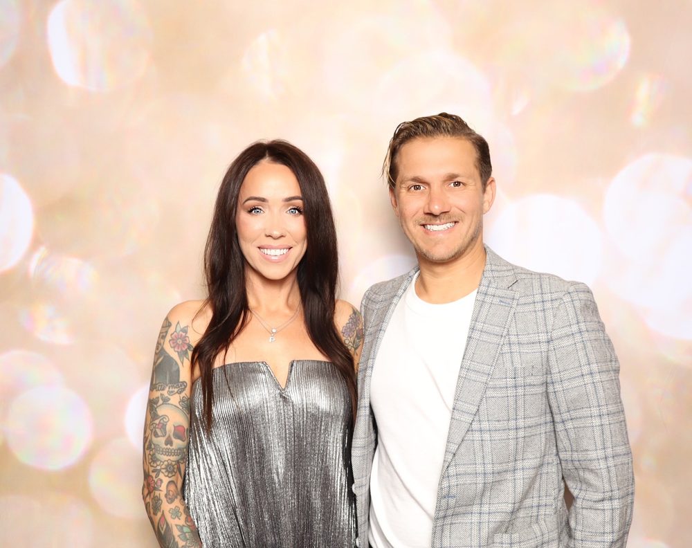 A couple posing at a black-tie charity gala photo booth in Virginia Beach
