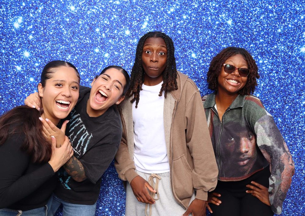 Four friends smiling at a Navy team event photo booth at Topgolf in Virginia Beach