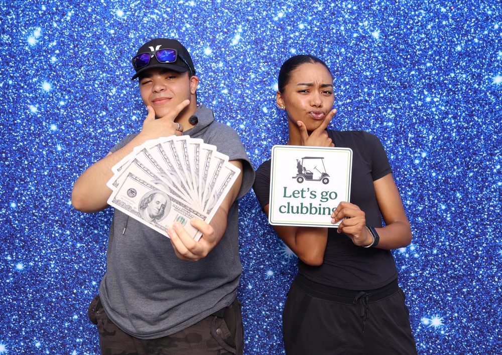 Two guests with a money fan and sign at a Navy team event photo booth in Virginia Beach