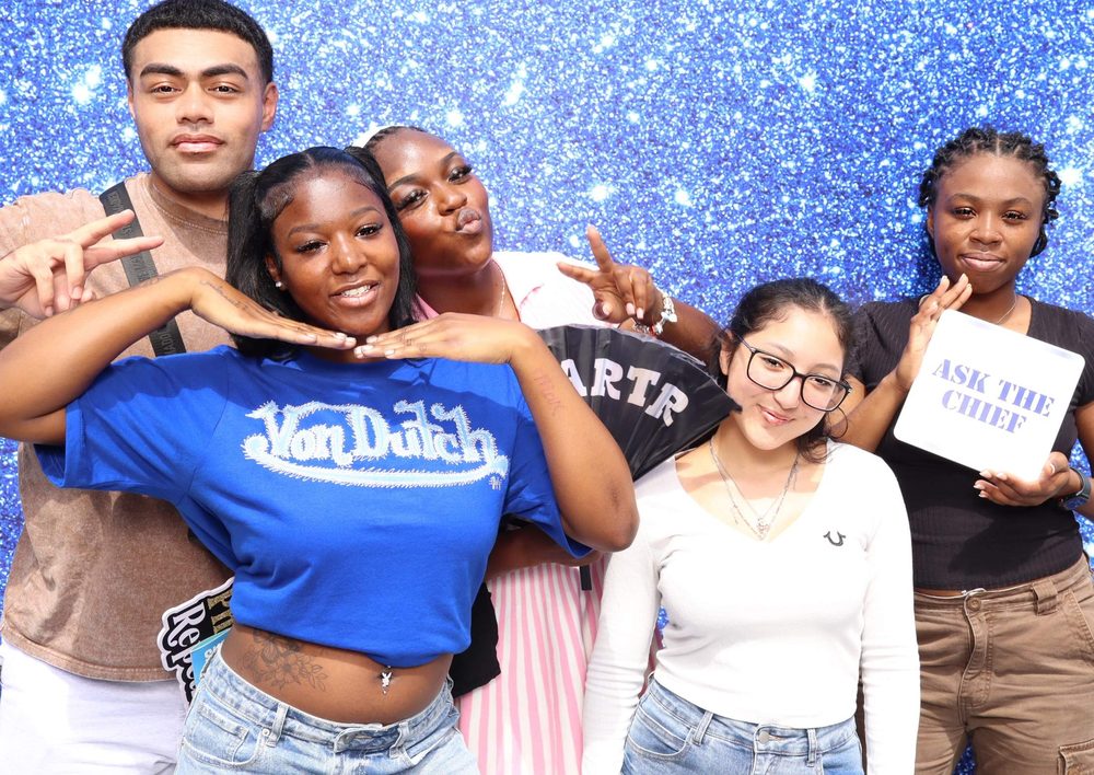 Five friends with props at a Navy team outing photo booth at Topgolf in Virginia Beach