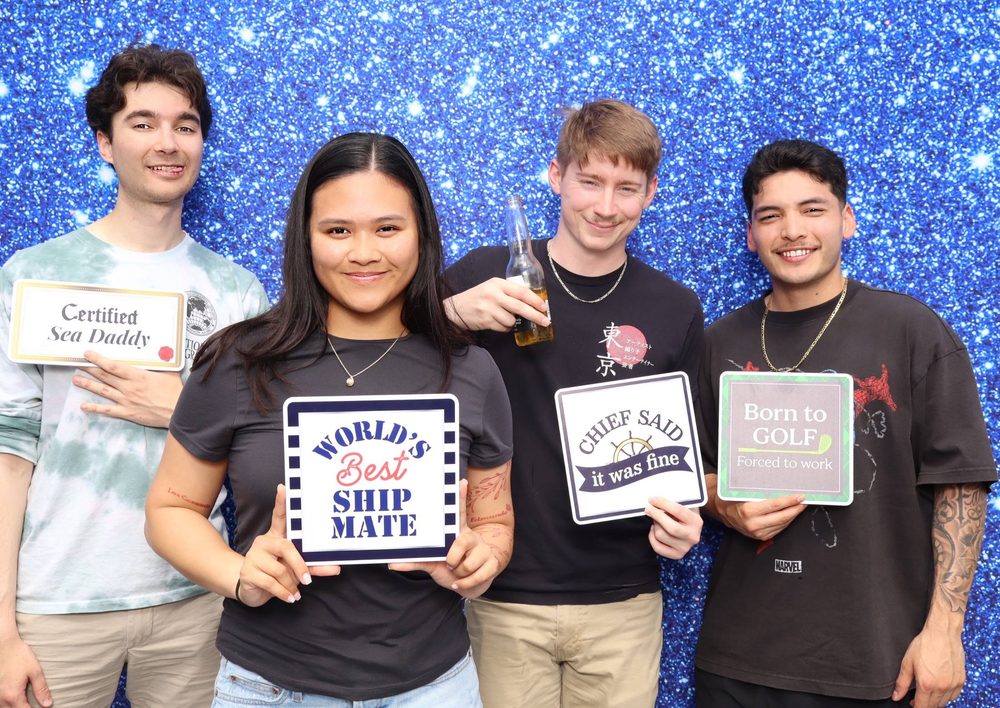 USS Eisenhower crew members holding World's Best Shipmate, Chief Said It Was Fine, and Born to Golf signs at a Topgolf event photo booth in Virginia Beach