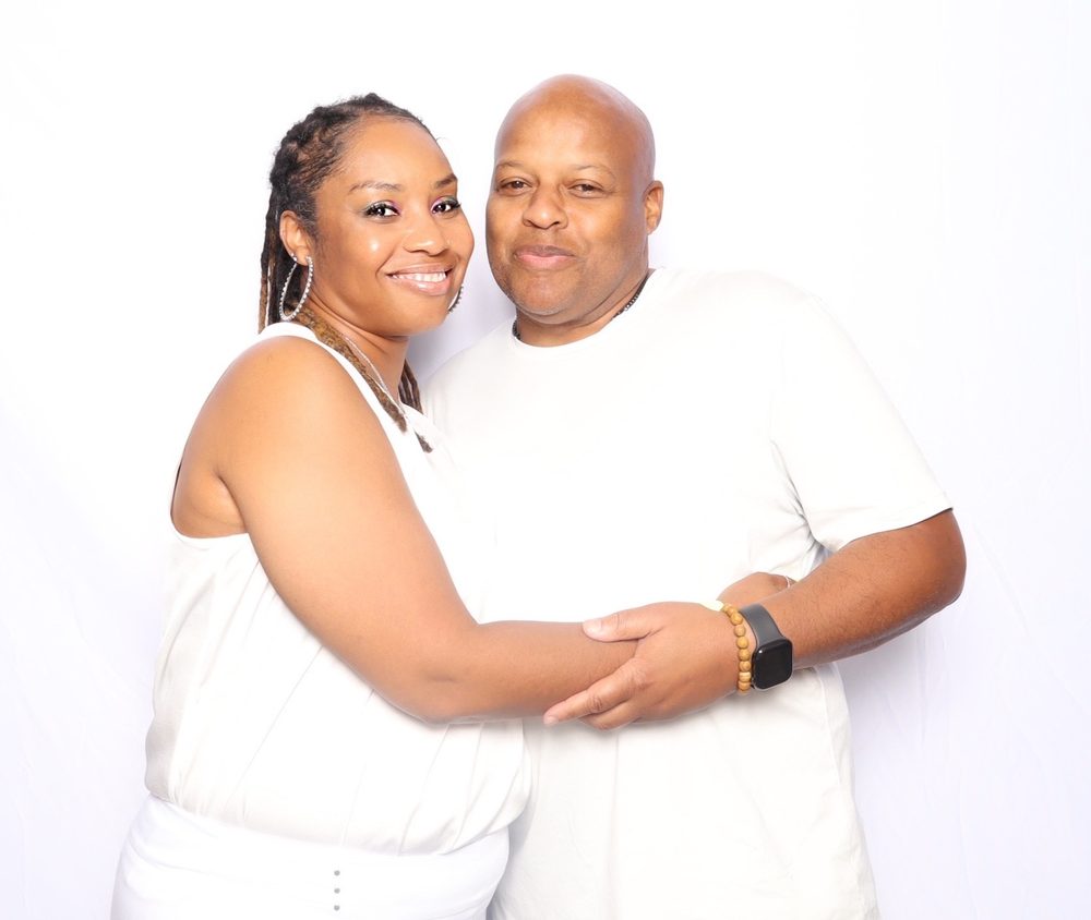 A couple in white hugging at an all-white party photo booth in Virginia Beach