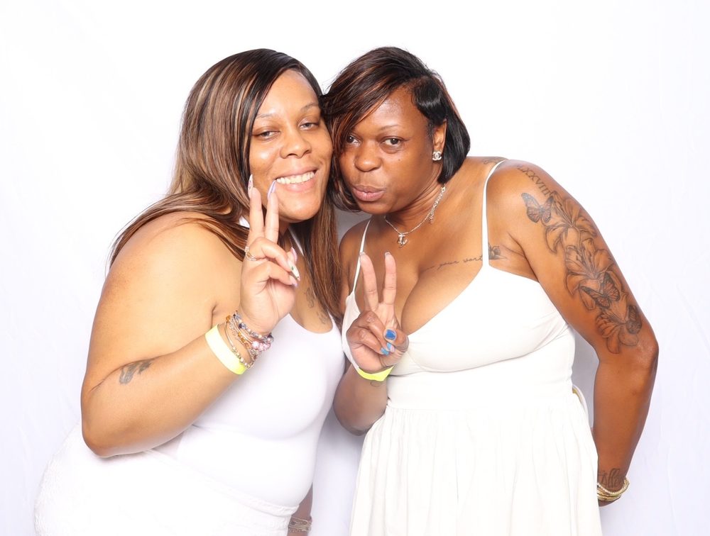 Two friends throwing peace signs on the All White night at the Beats on the Beach photo booth in Virginia Beach