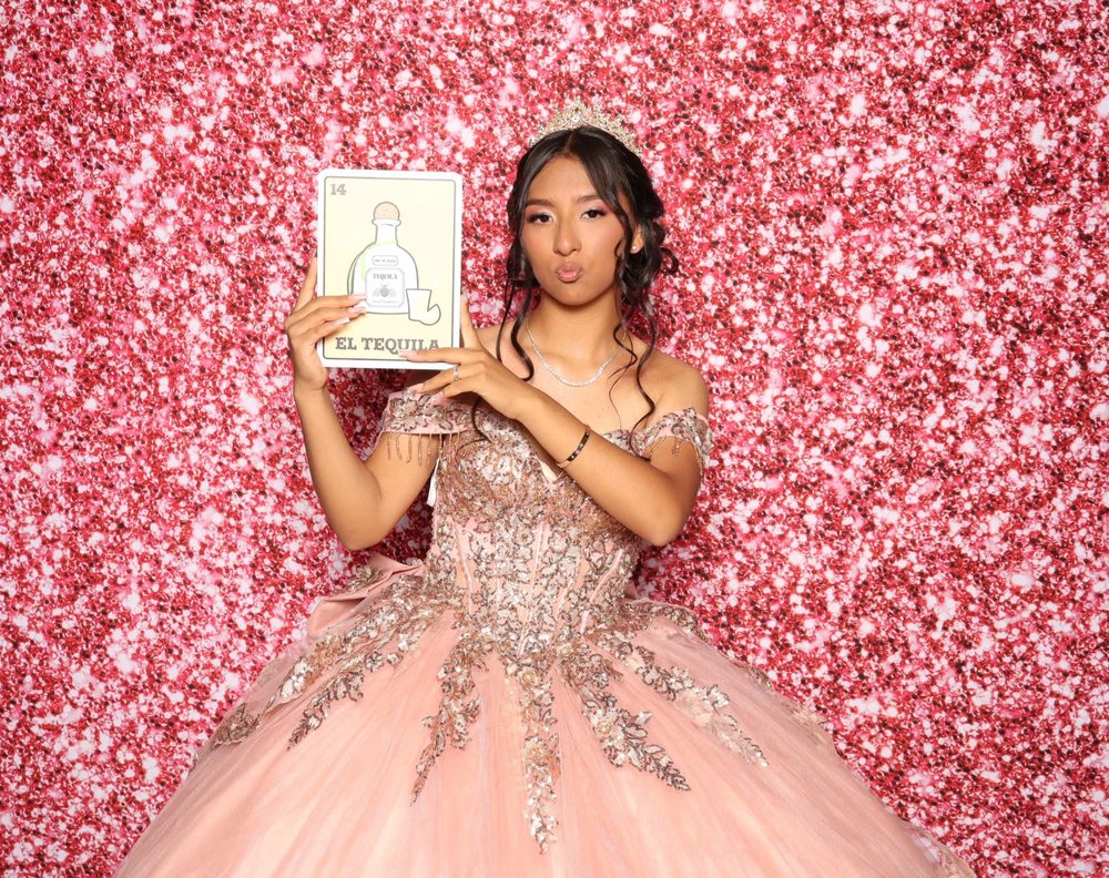 A quinceañera in a pink ball gown posing at a photo booth at The Armory in Perth Amboy