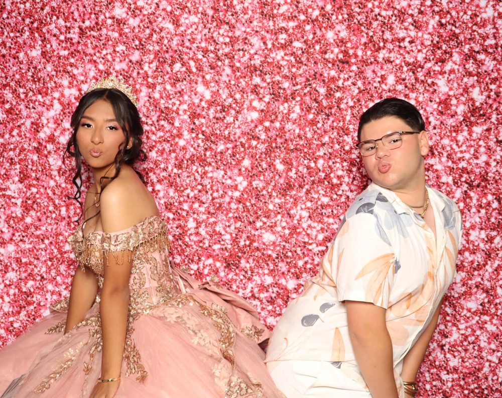 A quinceañera posing with a guest at her quince photo booth in Perth Amboy