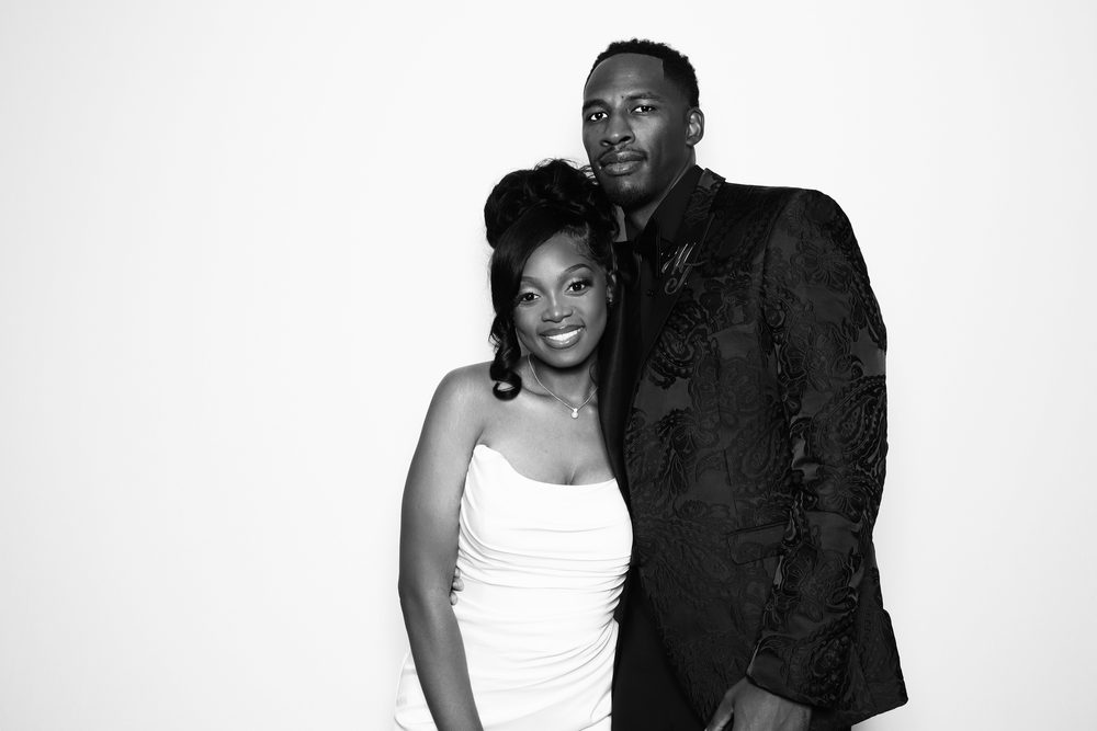 A bride and groom posing together at a black-and-white wedding photo booth in Chesapeake