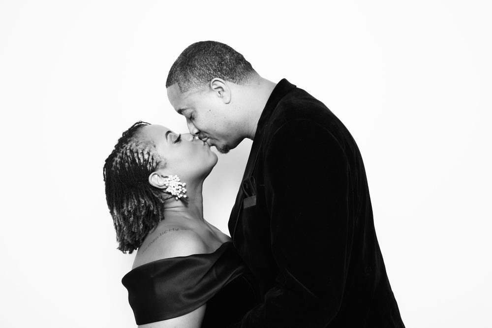 A couple sharing a kiss at a black-and-white wedding photo booth in Hampton