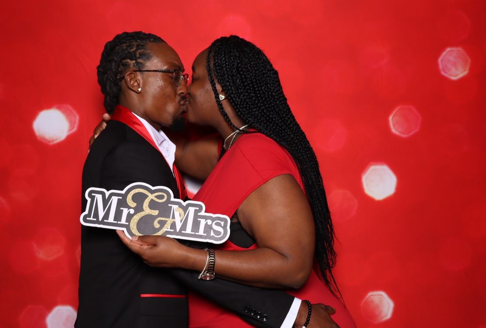 A couple kissing behind a Mr and Mrs sign at a wedding photo booth in Suffolk