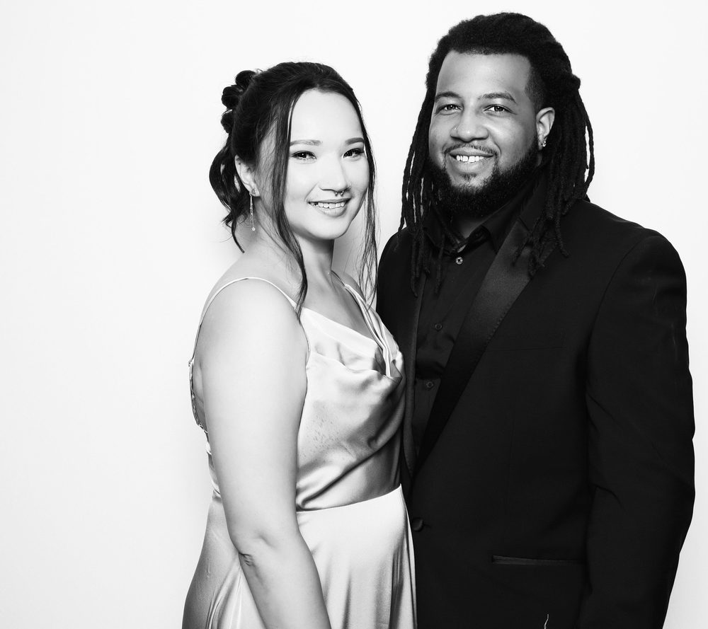 A stylish guest couple posing at a black-and-white wedding photo booth in Virginia Beach