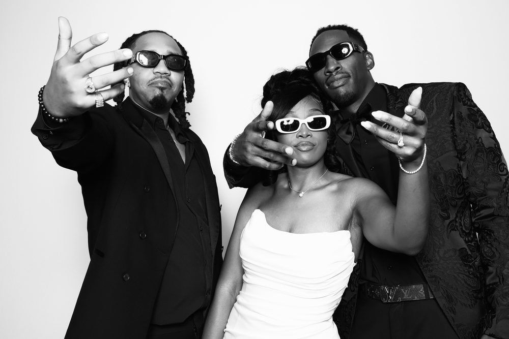 A bride in sunglasses posing with groomsmen at a Chesapeake wedding photo booth