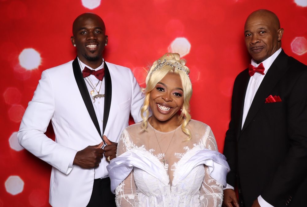 A bride and groom with a groomsman at a Suffolk wedding photo booth