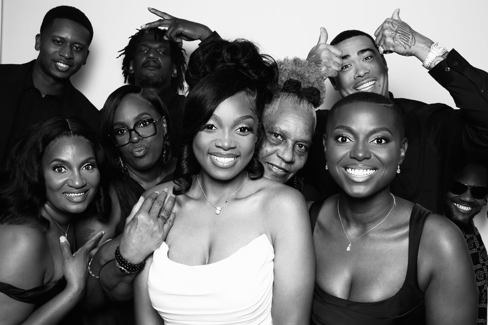 A bride surrounded by smiling friends at a black-and-white wedding photo booth in Chesapeake