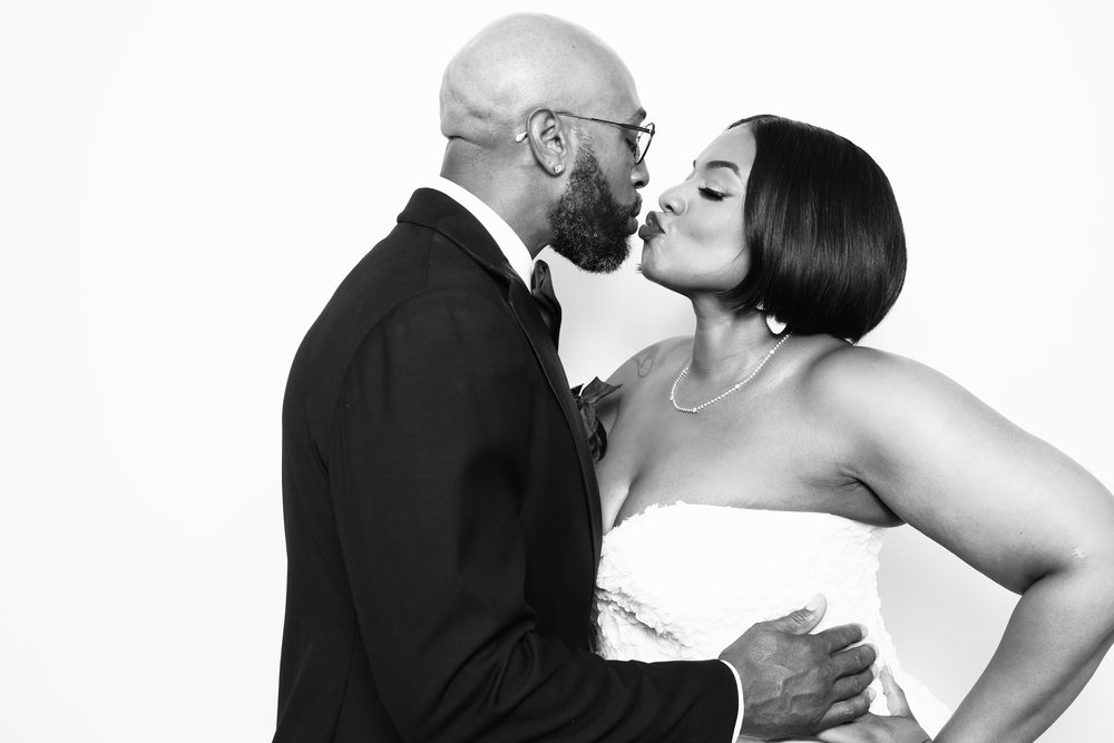 A bride kissing her groom at a black-and-white wedding photo booth in Hampton