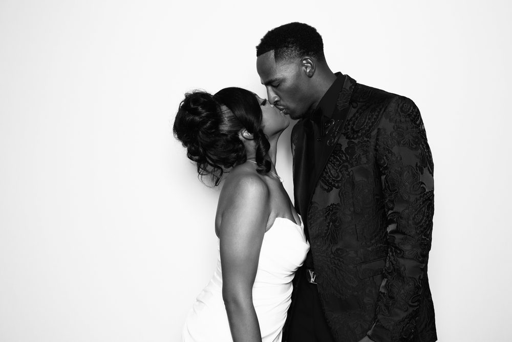 A groom kissing his bride at a studio-lit wedding photo booth in Chesapeake