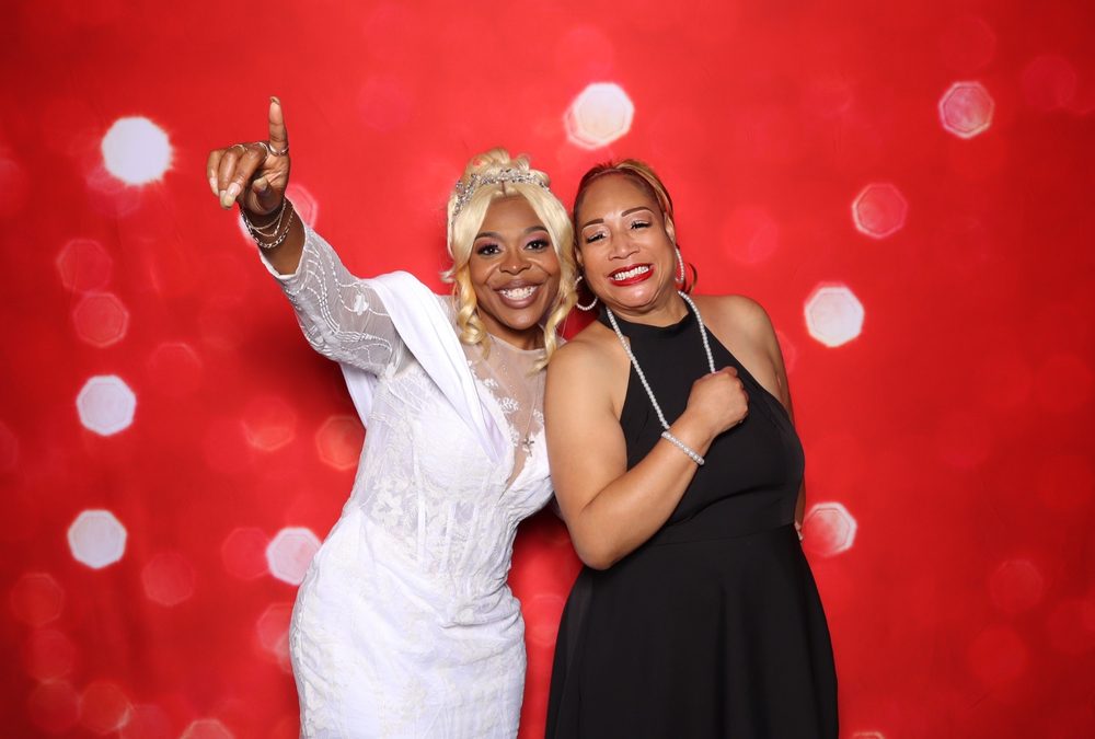 A bride and a friend celebrating at a Suffolk wedding reception photo booth