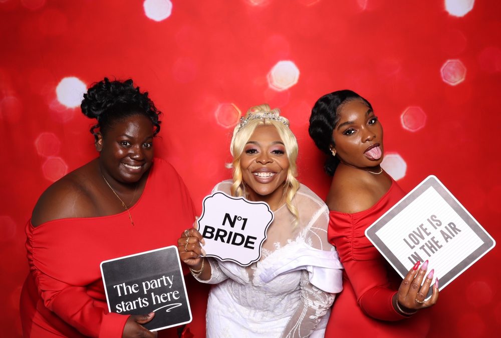 A bride and bridesmaids holding sign props at a Suffolk wedding photo booth
