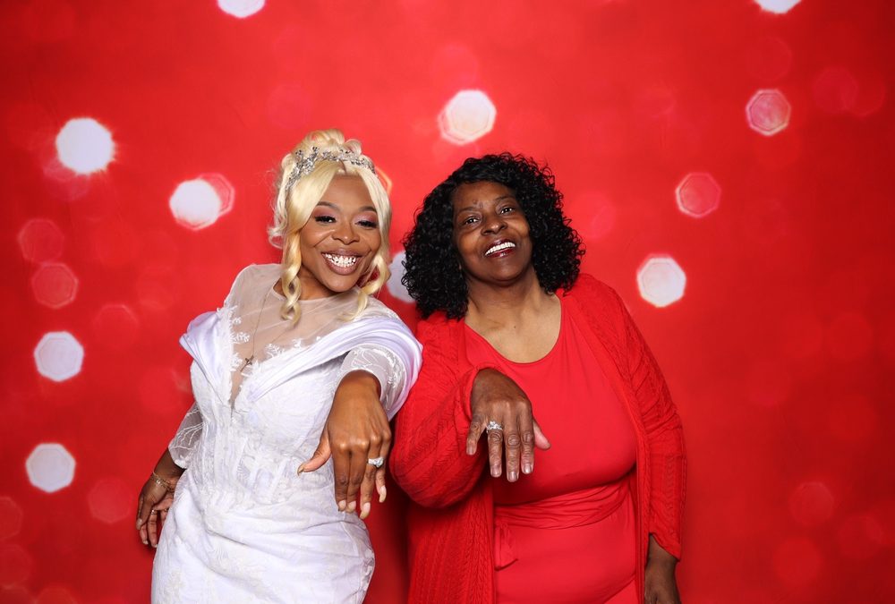 A bride and guest flashing their rings at a Suffolk wedding reception photo booth