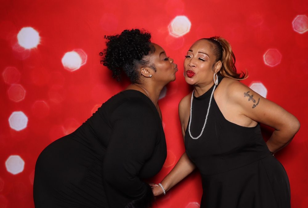 Two wedding guests going in for a kiss at a Suffolk wedding photo booth