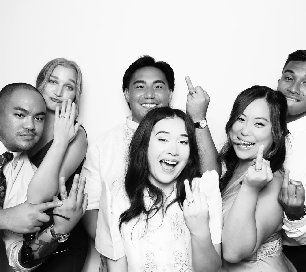 Newlyweds and friends showing off ring fingers at a black-and-white wedding photo booth in Virginia Beach