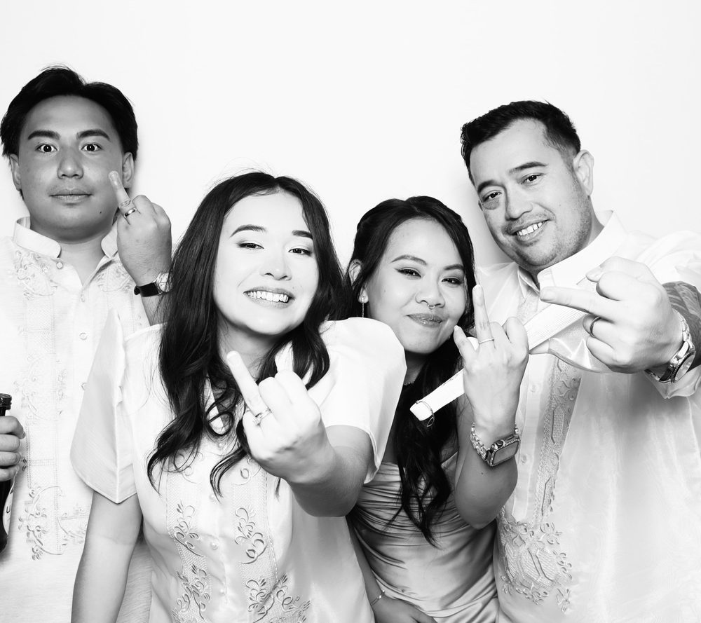 A bride and groom with friends showing their rings at a wedding photo booth in Virginia Beach