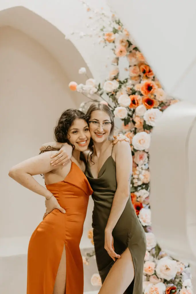 Wedding guests posing in a luxury photobooth with a floral backdrop and editorial lighting at a modern event